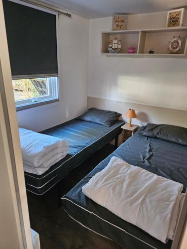 two beds in a room with a window at Mobil home 6 personnes in Saint-Brevin-les-Pins