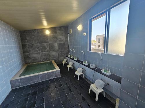 a bathroom with a tub and two toilets at Royal Hotel Uohachi in Toyota
