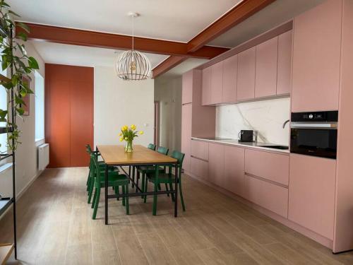a kitchen with a table with green chairs and pink cabinets at Unique design triplex with rooftop terrace in Mechelen