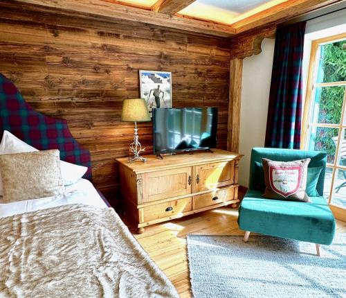 a bedroom with a bed and a tv and a chair at Mountain Suites by Belle-Stay in Kitzbühel