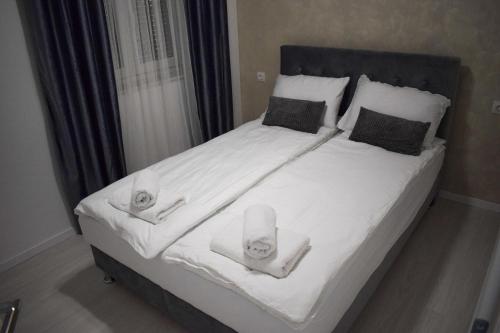Una cama grande con sábanas blancas y toallas. en Amal en Mostar