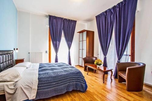 Schlafzimmer mit violetten Vorhängen sowie einem Bett und Stühlen in der Unterkunft Mammasisi Rooms in Lecce