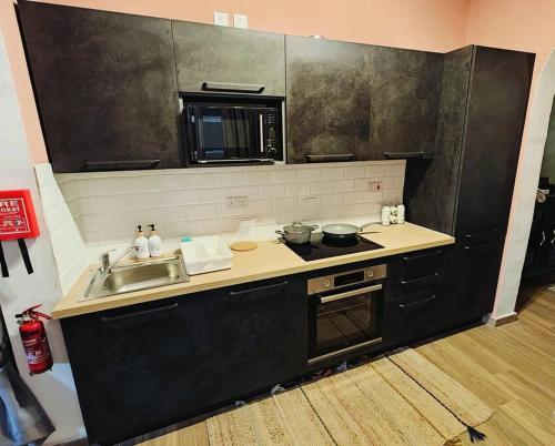 een keuken met een wastafel, een fornuis en een magnetron bij Cosy Apartment in Senglea in Senglea