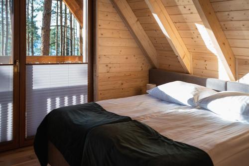 sypialnia z łóżkiem w drewnianym domku w obiekcie Osada Swory domki w lesie nad jeziorem w mieście Małe Swornigacie