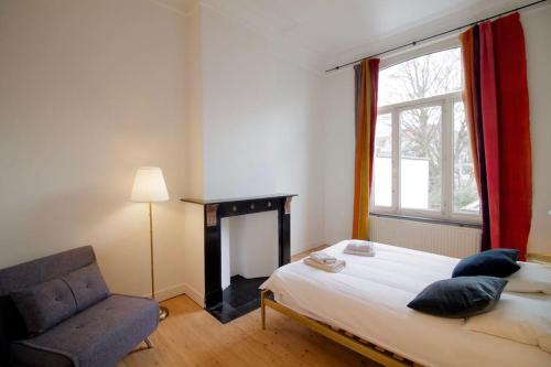 a bedroom with a bed and a chair and a window at Amazing 3 bedrooms - Place Brugmann in Brussels