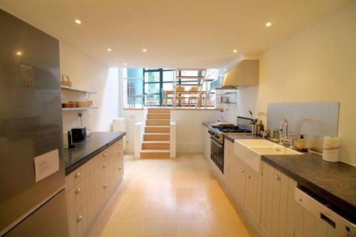 a kitchen with white cabinets and a staircase in it at Amazing 3 bedrooms - Place Brugmann in Brussels