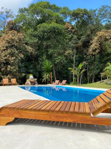 a wooden bench next to a swimming pool at Pousada Altitude 1200 in Fazendinha