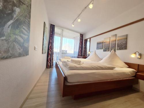 1 dormitorio con 1 cama grande con almohadas blancas en Kurhotel Schluchsee App 1103 - das mit der Kuckucksuhr, mit Indoorpool, Hochschwarzwaldkarte, Schluchsee, en Schluchsee