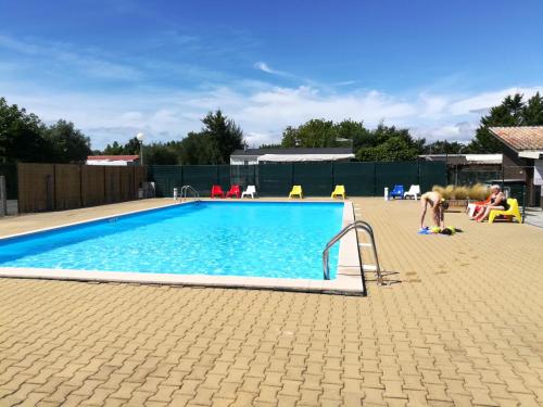 une grande piscine avec une personne debout à côté de celle-ci dans l'établissement Mobil-Home 54 au Parc Résidentiel de la Plage - 4 personnes, à Gujan-Mestras