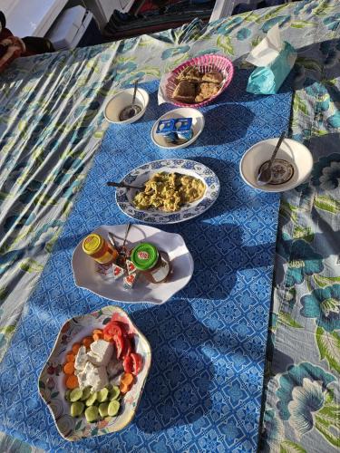 a table with plates of food on a blue table cloth at Felucca Sailing Boat Overnight Experience in Aswan