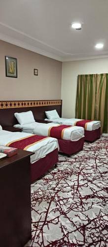 three beds in a hotel room with a carpet at فندق لؤلؤة نور توصيل مجاني للحرم 24 ساعة in Az Zāhir