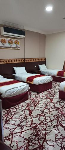 a hotel room with three beds and a carpet at فندق لؤلؤة نور توصيل مجاني للحرم 24 ساعة in Az Zāhir