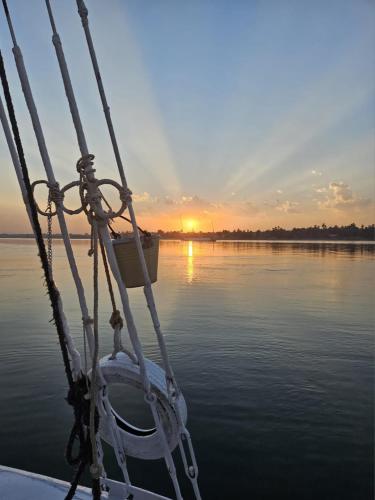 a boat in the water with the sunset in the background at Felucca Sailing Boat Overnight Experience in Aswan