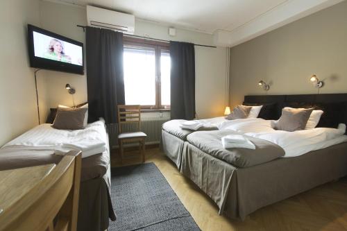a hotel room with two beds and a flat screen tv at Park Hotell in Luleå