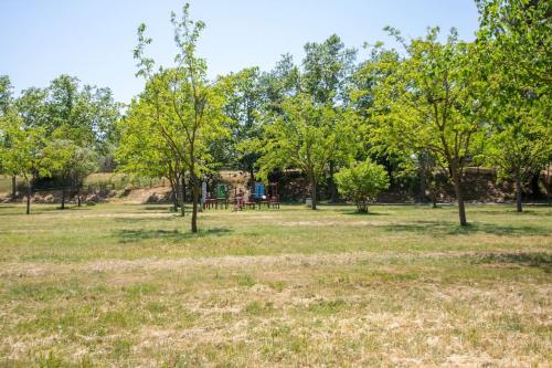 um parque com árvores e um parque infantil ao fundo em TRA9-CASA con BARBACOA, PISCINA comunitaria en verano, 5 min en coche del MAR y el CENTRO em Empuriabrava