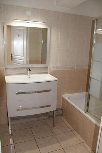 une salle de bain avec un lavabo, un miroir et une baignoire dans l'établissement Appartement F4 en résidence Rez de Jardin, à Fréjus
