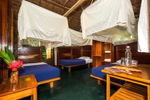 a room with two beds and a table and chairs at Hacienda Herrera Tambopata in Puerto Maldonado