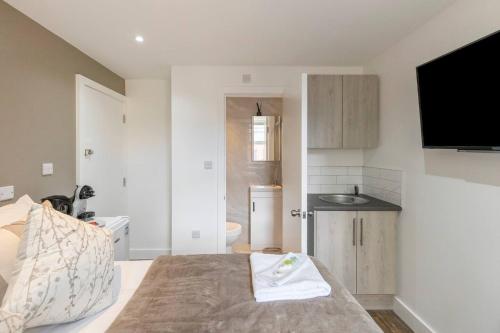 a small bedroom with a bed and a kitchen at Modern Studio Retreat Near Shop's! in Ealing