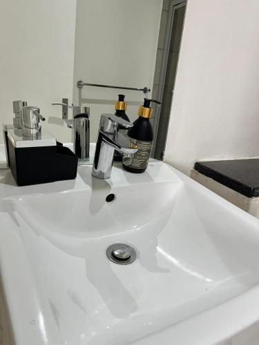 DMN City Junction Apartment في ويندهوك: بالوعة حمام بيضاء وعليها صنبور