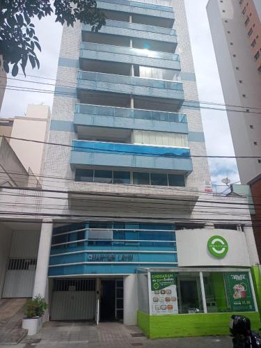 a tall building with a building with blue windows at Apart Quartier Latin in Vitória