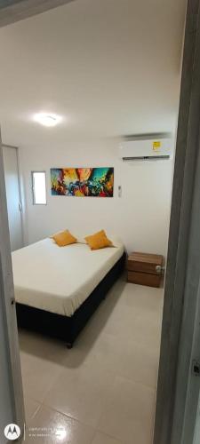 1 dormitorio con 1 cama y una pintura en la pared en Como en casa, en Barranquilla