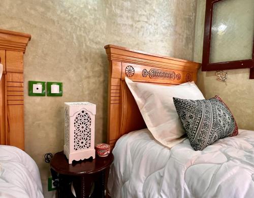 a bedroom with a bed with a wooden headboard at Riad de charme - la perle des Oudayas in Rabat