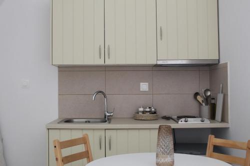 a kitchen with white cabinets and a sink at 200 year old 'Kamara Suite' with private garden in Pirgos Dhirou
