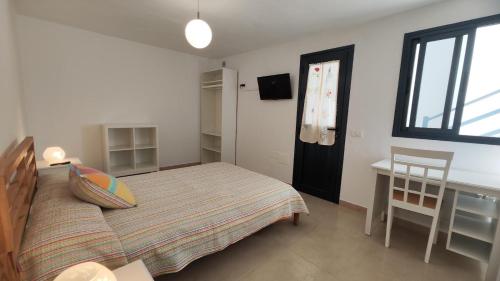 een slaapkamer met een bed, een bureau en een raam bij La Caracola 3 Hab Con Solarium A 1min De La Playa in La Restinga