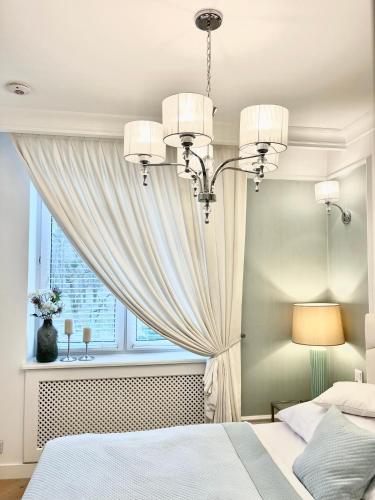 een slaapkamer met een bed en een raam met een kroonluchter bij Apartament Royal in Częstochowa