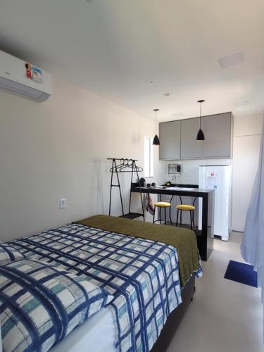 Un dormitorio con una cama y una mesa y una cocina. en Eco Loft Brisa do Mar, en Cabo Frío