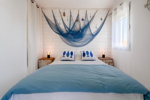 a bedroom with a bed with a net on the wall at LA PERLE DU SUD : Classement officiel 3 étoiles + 2 Clés Clévacances in Frontignan