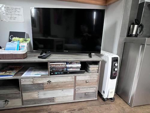 a flat screen tv on a wooden entertainment center at Tiny House Black Pearl in Tettnang
