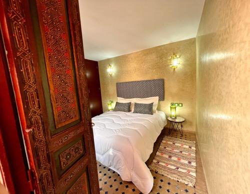 una camera da letto con letto, lenzuola e cuscini bianchi di Riad de charme - la perle des Oudayas a Rabat