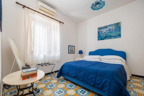 Un dormitorio con una cama azul y una mesa. en Casa Simona - Positano Center - 5 min to the beach, en Positano
