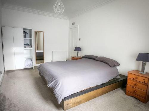 een slaapkamer met een bed, een dressoir en een spiegel bij Central 2-bedroom bunglow with double sofa bed in Carnoustie