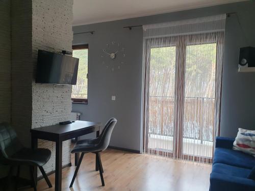 - un salon avec une table, des chaises et une télévision dans l'établissement Apartament Przytulny, à Karwia