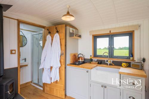 uma cozinha com armários brancos, um lavatório e uma janela em One Of A Kind Shepherds Hut With Incredible Views em Thame