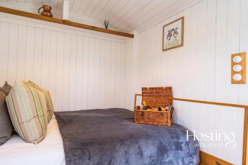 a bedroom with a bed with a basket on it at One Of A Kind Shepherds Hut With Incredible Views in Thame