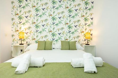 1 dormitorio con 1 cama blanca grande y papel pintado tropical en New! La Casa del cerrajero, en Sevilla