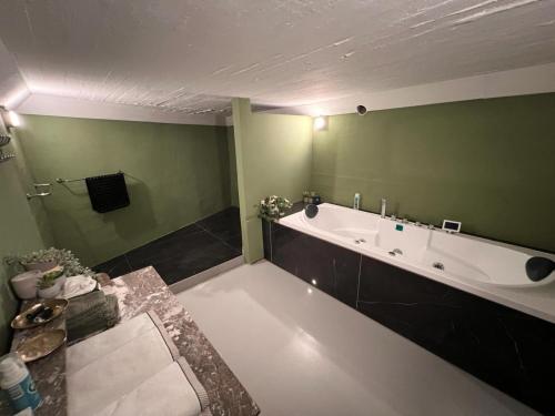a bathroom with a tub and a green wall at Charmante Art Deco rijwoning in Ostend