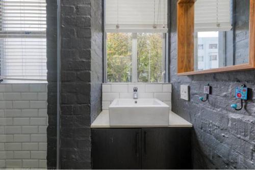 a bathroom with a white sink and a window at Central Studio on Main in Cape Town