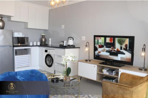 een keuken en een woonkamer met een tv en een bank bij Barcalla Hotel Apartments in Maseru