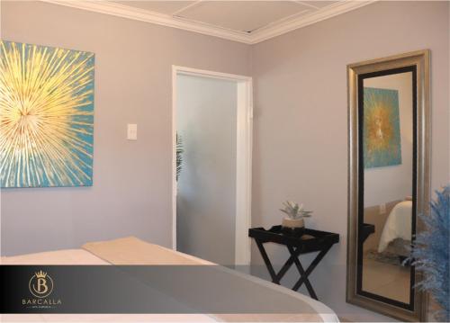 a bedroom with a painting on the wall and a mirror at Barcalla Hotel Apartments in Maseru