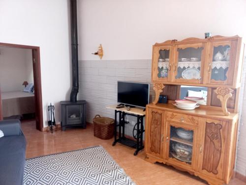 a living room with a wooden cabinet and a television at O Refúgio dos Pais in Bordeira