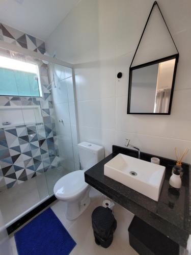 een badkamer met een wastafel, een toilet en een spiegel bij Eco Loft Brisa do Mar in Cabo Frio
