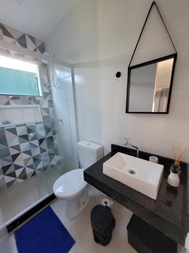 Un baño con lavabo, inodoro y espejo. en Eco Loft Brisa do Mar, en Cabo Frío