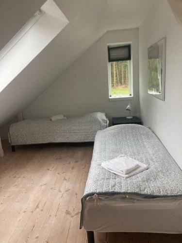 a attic bedroom with two beds and two windows at Bøllingsø Feriehus in Silkeborg