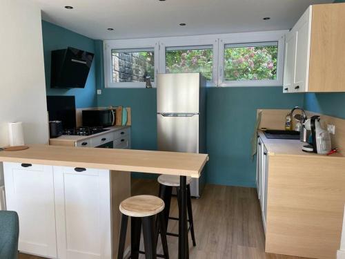 een keuken met blauwe muren en een aanrecht met krukken bij Jolie maison à Equihen-Plage in Équihen-Plage