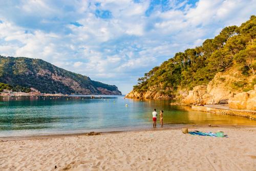 two people standing on a beach near the water at Villa Hermosa in Begur