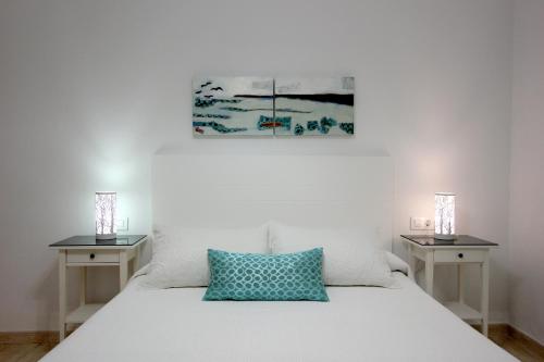 コニル・デ・ラ・フロンテーラにあるApart ConiL Benaventのベッドルーム1室(白いベッド1台、ナイトスタンド2台、絵画付)